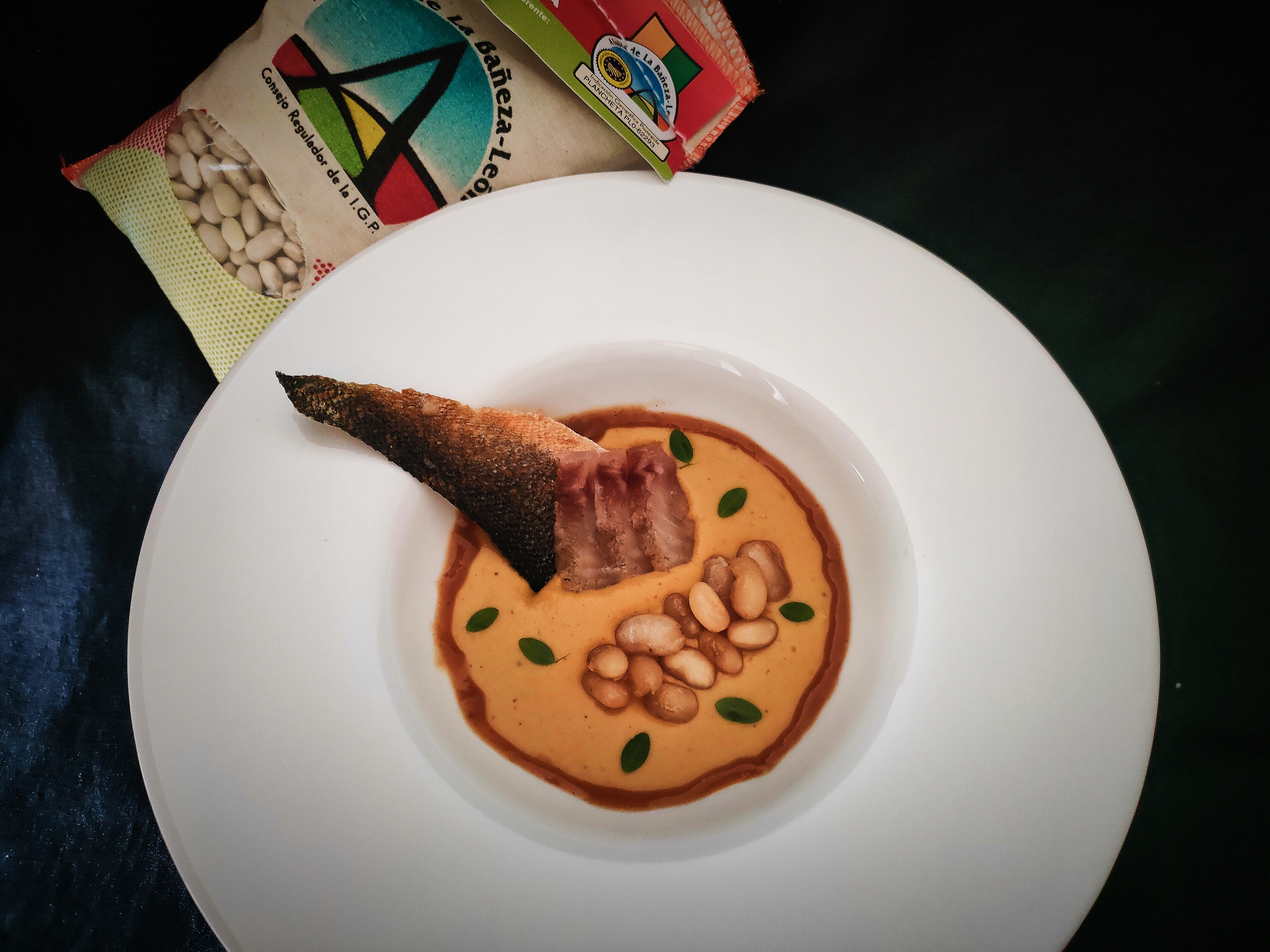 Crema templada de alubias plancheta al curry y glaseadas con salsa cítrica, lubina curada y caldo tostado de sus espinas