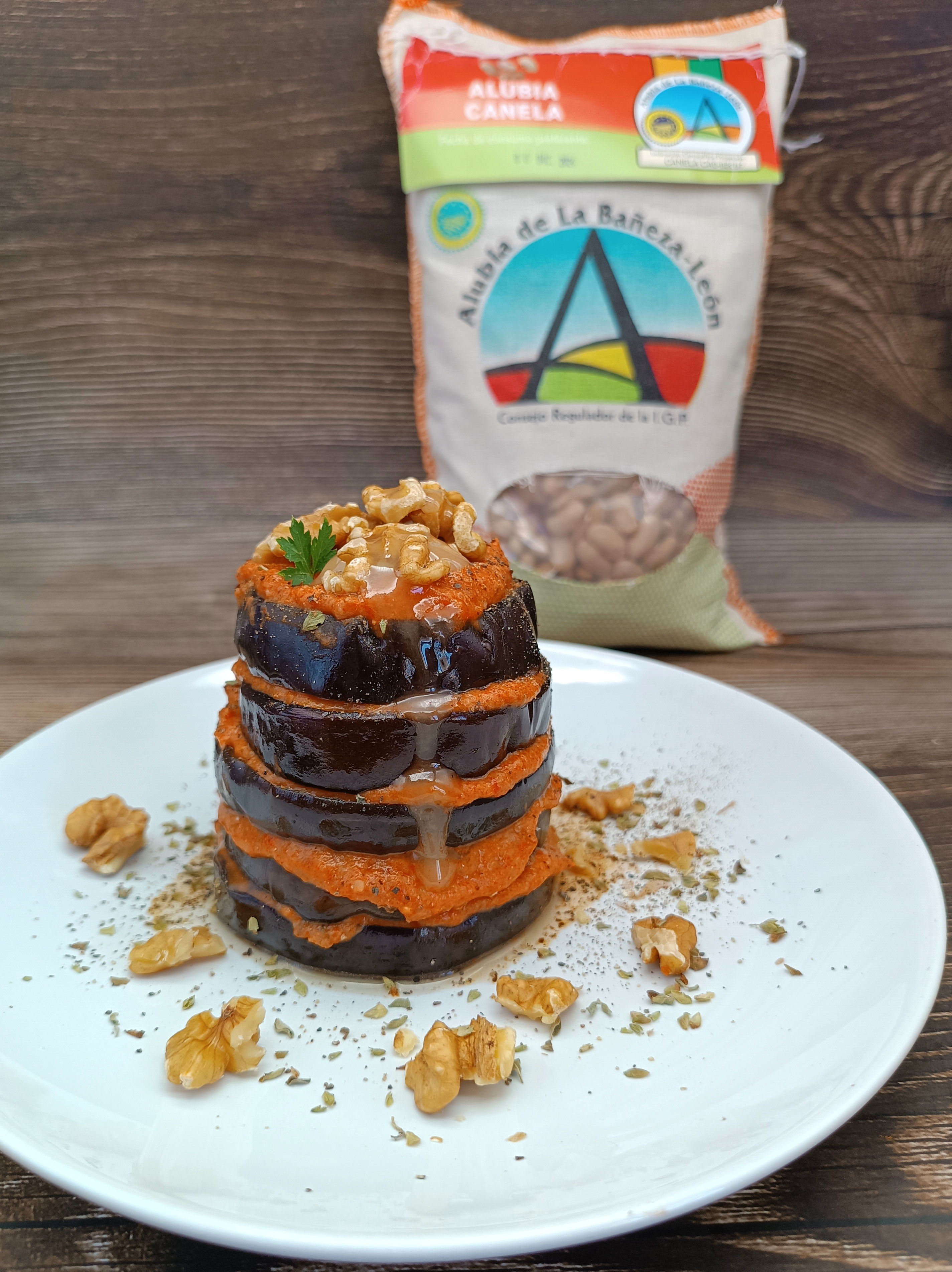 Milhojas de berenjena con crema de alubias, piquillos y feta, coronado con nueces.